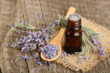 Herbal oil and lavender flowers on old wooden background
