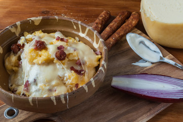 Polenta with cheese and sausages on rustic wooden table	
