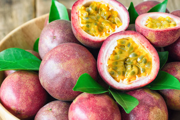 Close up fresh passion fruit in wood bowl on wood table in side view with copy space for background or wallpaper. Ripe passion fruit so delicious sweet and sour. Tropical fruit. Macro concept. - obrazy, fototapety, plakaty