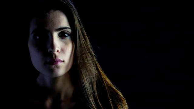 Portrait of sad woman in the dark looking camera