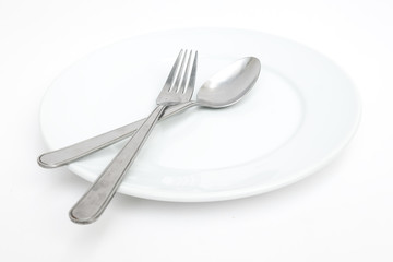 empty new ceramics plate with spoon and fork on white background