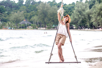 girl stands on a swing on the beach of Thailand