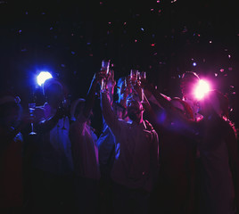 Group of young people celebrating new year with champagne at night club