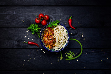 Traditional asian noodle lagman with vegetables and meat. Top view dark wooden background