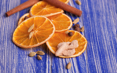 Dry slices of orange, cinnamon, ginger and cardamom, on a blue wooden background. Aromatic spices. Christmas decorations.