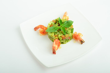 Salad with shrimps, avocado, cherry tomatoes decorated basil on a plate isolated on white background