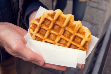 Man's Hands Holding a Warm Liege Style Belgian Waffle Wrapped in Paper