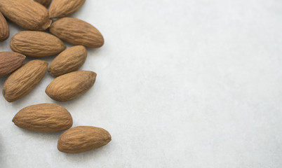 Close up dried almonds on left side white grey background