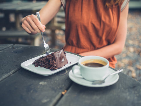Young woman eating cake and drinking coffee