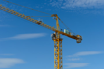 yellow tower crane against the blue sky with clouds