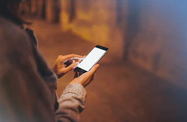 Girl pointing finger on screen smartphone on background illumination glow bokeh light in night atmospheric city, hipster using in hands mobile phone, mockup glitter street, online internet concept