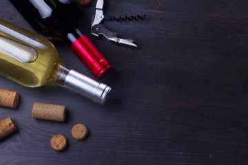 Bottles of red and white wine with corks on dark wooden table