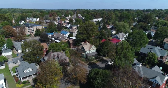 A daytime slow reverse aerial establishing shot of a residential neighborhood in Salem, Ohio.  	