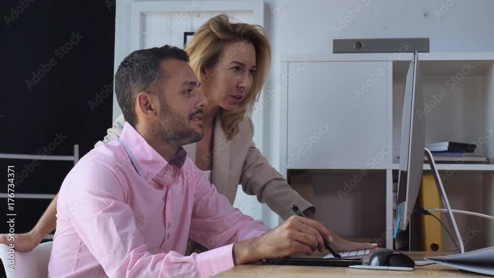 Aufkleber Two designers talking about project. Handsome man drawing using digital tablet near standing caucasian woman looking on display computer with happy smile
