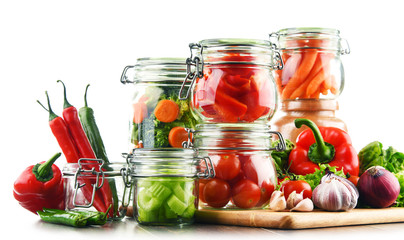 Fototapeta na wymiar Jars with marinated food and raw vegetables isolated on white