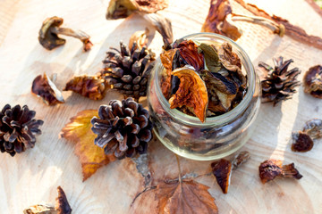 Dried mushrooms in jar on wooden background.