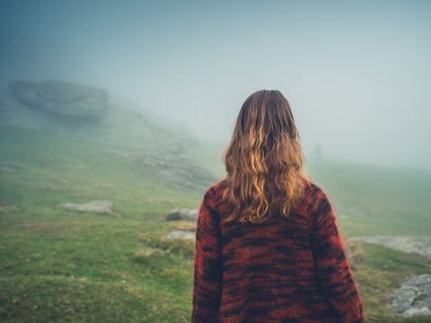 Young woman walking in the fog on moor