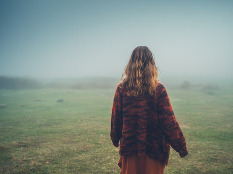 Young woman walking in the fog on moor