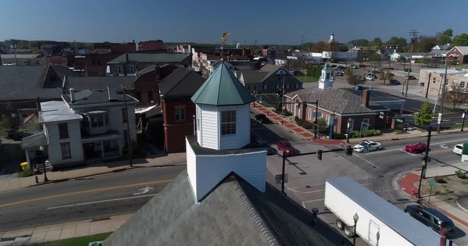 A laterally-moving daytime dolly aerial establishing shot of the small town of Salem, Ohio's business district.  	