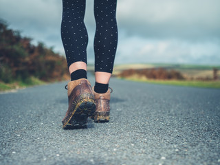 Feet of young woman walking on country road