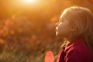 Little girl relaxing on sunset with closed eyes