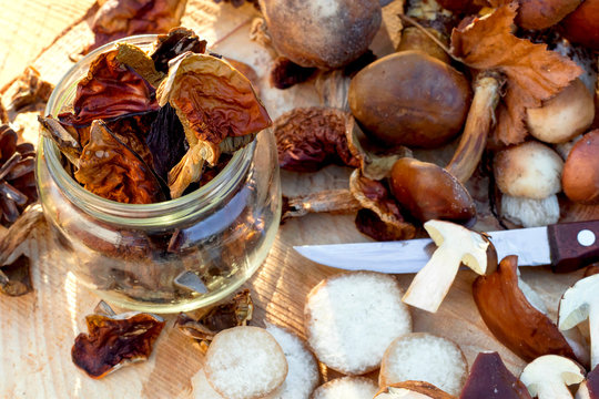 Prepare dried mushrooms. Autumn still life of mushrooms and flowers on wooden background.