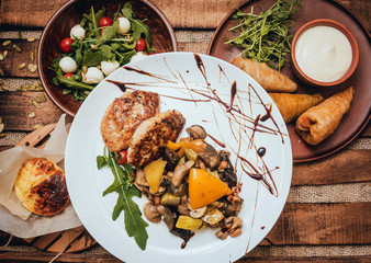 Tasty meat rolls with sour cream and salad on wooden table