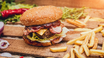 Bacon burger with beef and french fries on wooden table