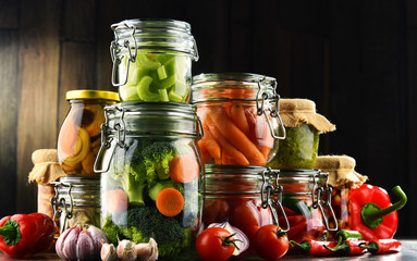 Jars with marinated food and organic raw vegetables