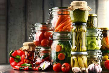 Jars with marinated food and organic raw vegetables
