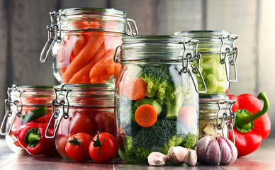 Jars with marinated food and organic raw vegetables