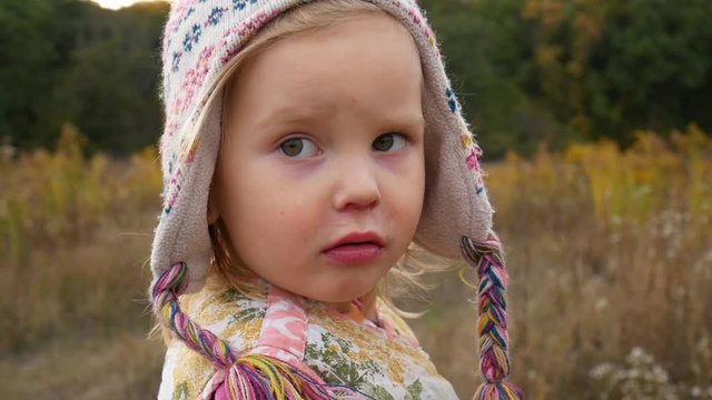 Little girl in the autumn forest. The child is somewhat agitated and worried and informs about this by turning to the camera.