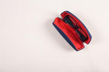 Fototapeta na wymiar eyeglass and red boxed on fabric background.