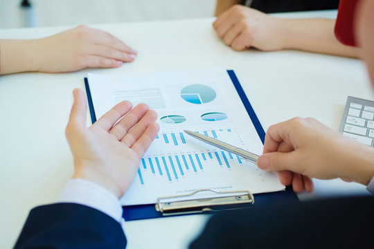 Businessman pointing at analytic financial market chart. Business people present accounting graph report summary at workplace. Start up young man shows statistics performance at office.