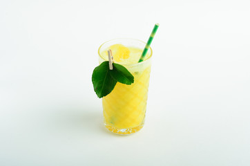 Yellow lemonade with ice decorated leaves in glass isolated on white background