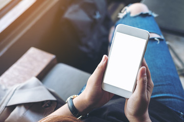 Mockup image of woman's hands holding white mobile phone with blank black screen on thigh