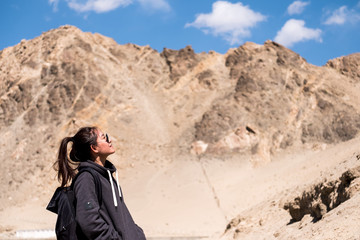 Portrait image of a beautiful Asian woman tourist standing in front of mountain and blue sky background
