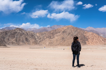 Portrait image of a beautiful Asian woman tourist standing and turn back in front of mountain and blue sky background