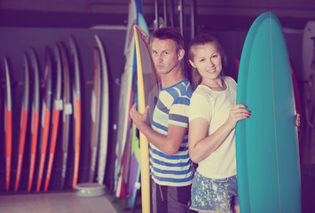 Young man and woman satisfied of choose surfboard