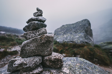 Human-made pile of stones - cairn as way marker in foggy mountain © Soloviova Liudmyla