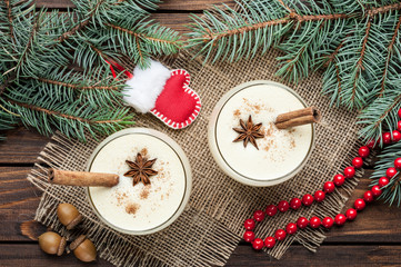 eggnog cocktail in glasses arranged with christmas decoration on wooden table
