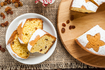 Fototapeta premium homemade traditional fruit cake slices on white plate decorated with raisins on wooden table top view