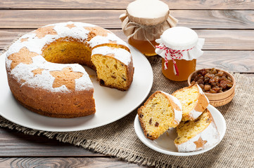 homemade traditional fruit cake slices on white plate decorated with nuts and honey jar at wooden table