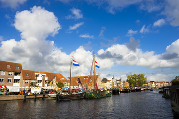 Netherlands Leiden Galgewater, a bright sunny day with a clear blue sky and clouds and with houses along side the Galgewater canal with boats resting in the water.