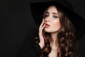 Beautiful Fashion Model Woman with Perfect Wavy Hair and Makeup. Young Model in Black Hat