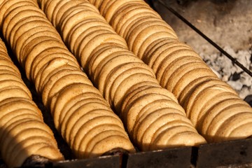 Trdelnik - traditional national czech street desert, baking on the street. Preparation of a sweet snack on the grill.