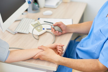 Closeup of doctor measuring blood pressure of female patient using automatic blood pressure monitor