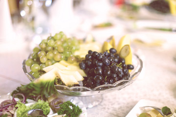 Assorted fresh fruits on plate apple grapes kiwi pineapple grapefruit orange banana and mint