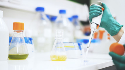 Close up of woman scientist s hands taking some yellow liquid to examine. Uni assessment.