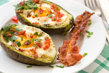 Eggs baked in avocado with bacon, red paprika and chive.